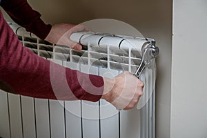 Worker hands repairing radiator with wrench.