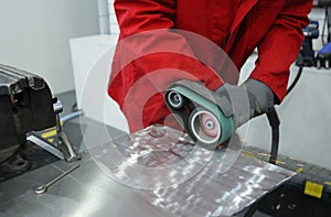 Worker hands sanding metal sheet by the hand held belt sender