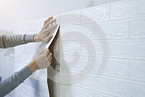 Worker hands sticking wallpaper on wall.