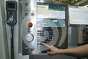 Worker hands touching the button on the board of computer numerical control of the milling machine