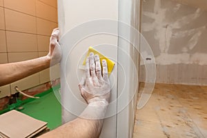 Worker hands is troweling by sandpaper the room wall in an apartment is inder construction, remodeling, renovation photo