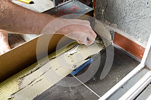 Worker hands using spatula and plastering ceiling with putty. Mesh on split. Closeup