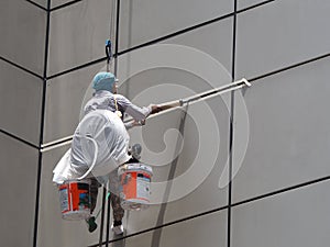 Worker hang from roof of building for maintenance out side of building under sunshine