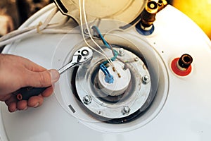 The worker has finished servicing the boiler and tightens the last nuts.close up