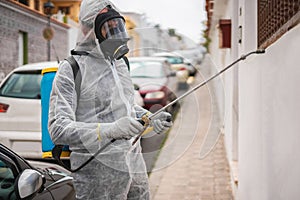 Worker in hazmat suit wearing gas mask protection while making disinfection in city street - Coronavirus decontamination for