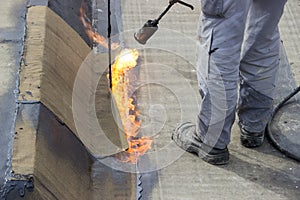 Worker heating and melting bitumen felt