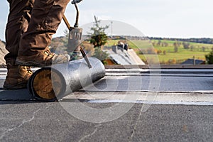 Worker Heating and melting bitumen roofing Flat roof installation