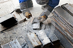 Worker in heavy industry or metallurgy beats scale off iron plates with hammer. Work with metal. Authentic workflow.