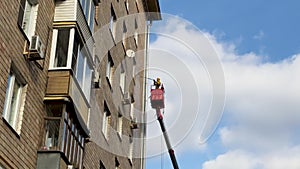 A worker at height cleans the wall of the apartment building with a high pressure device.