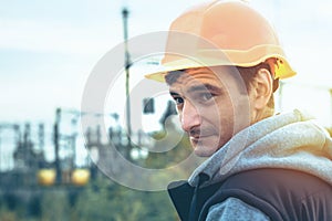 Worker in a helmet against the background of a substation