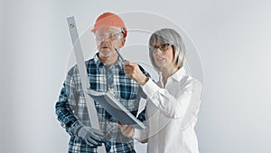 A worker in a helmet and a female engineer with a tablet and a level in their hands discuss plans for the reconstruction