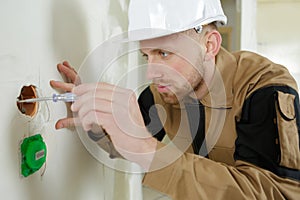 Worker in helmet outting wires in new building