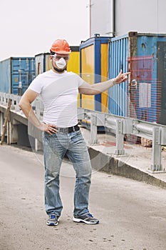 Worker in a helmet and a protective mask stands at the container