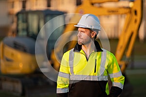 Worker in helmet on site construction. Excavator bulldozer male worker. Construction driver worker with excavator on the