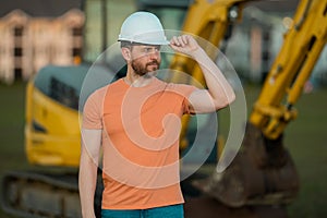 Worker in helmet on site construction. Excavator bulldozer male worker. Construction driver worker with excavator on the