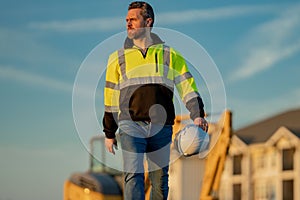 Worker in helmet on site construction. Excavator bulldozer male worker. Construction driver worker with excavator on the