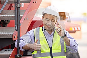 Worker helmet standing and talking on mobile phone at logistic cargo containers shipping yard