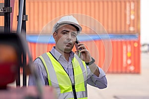Worker helmet standing and talking on mobile phone at logistic cargo containers shipping yard