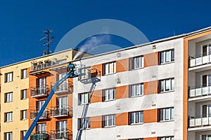 Worker with high pressure washer cleaning house facade