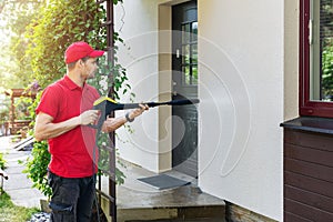 Worker with high pressure washer cleaning house facade photo