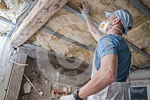 Worker in His 30s Replacing Old Attic Mineral Wool Insulation