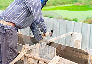 Worker hit nails on wood bar for support formwork