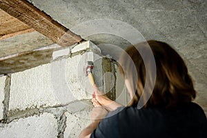 Worker hitting block wall using hammer