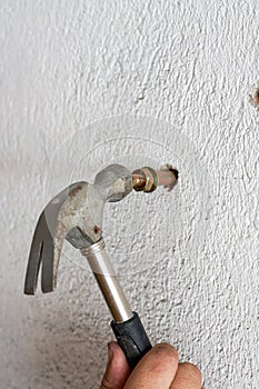 A worker is hitting a screw on the wall with a hammer