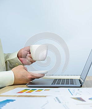 worker hold coffee cup above laptop with copy space