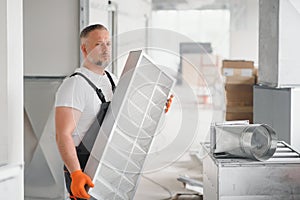 Worker holding air filter for installing in the office ventilation system. Purity of the air concept.