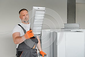 Worker holding air filter for installing in the office ventilation system. Purity of the air concept.