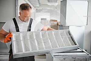 Worker holding air filter for installing in the office ventilation system. Purity of the air concept.