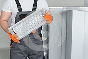 Worker holding air filter for installing in the office ventilation system. Purity of the air concept.