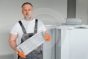 Worker holding air filter for installing in the office ventilation system. Purity of the air concept.