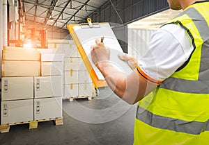 Worker Holding Clipboard is Control Loading Package Box into Cargo Container. Trucks Loading at Dock Warehouse. Shipment Boxes.
