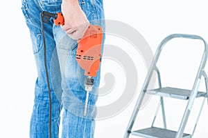 Worker holding drill in front of step ladder