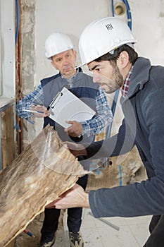 worker holding insulation sheet from wall