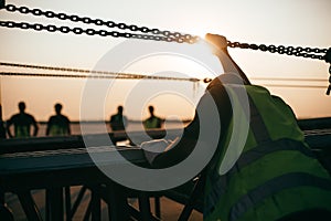 Worker holding an iron chain against sunset