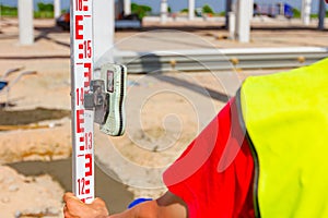 Worker is holding leveling rod to measuring level on construction site