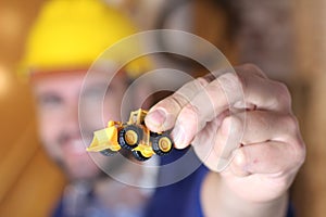 Worker holding miniature construction vehicle