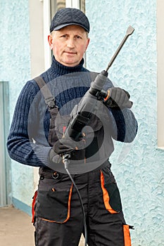 Worker holding a perforator in front of the house