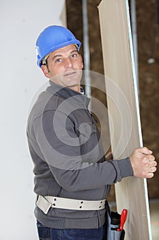 worker holding plywood at construction site