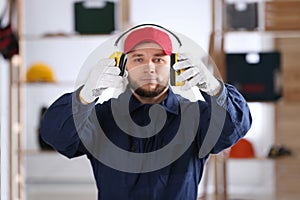 Worker holding safety headphones indoors, focus on hands. Hearing protection device