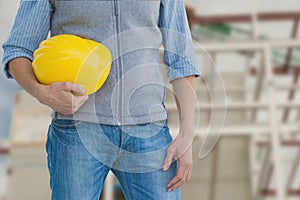 Worker holding a yellow helmet against construction