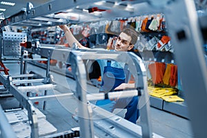 Worker holds aluminum stepladders in tool store