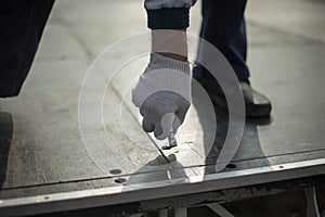 Worker holds bolt. Man tightens screw. Guy assembles structure. Fitting to hole