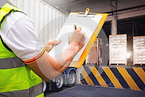Worker Holds A Clipboard and Inspects A Package Loading Boxes at A Distribution Warehouse. Shipping Freight Truck Logistic