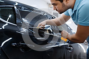 Worker holds film, car tinting installation