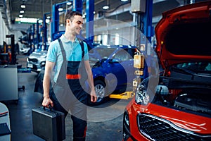 Worker holds a toolbox, car service station