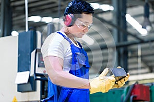 Worker in industrial factory checking work piece